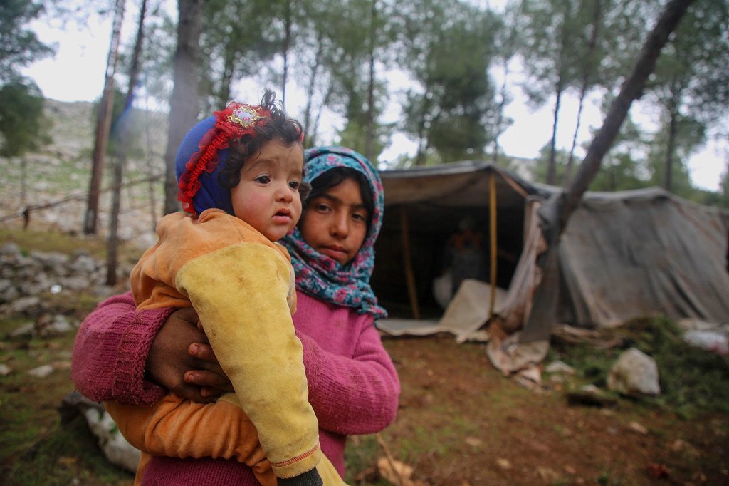 في 7 شباط/فبراير، طفلة تحمل طفلا مع نزوح الأطفال والعائلات من جنوب إدلب وغرب حلب باتجاه المناطق الشمالية من إدلب وحلب في سوريا