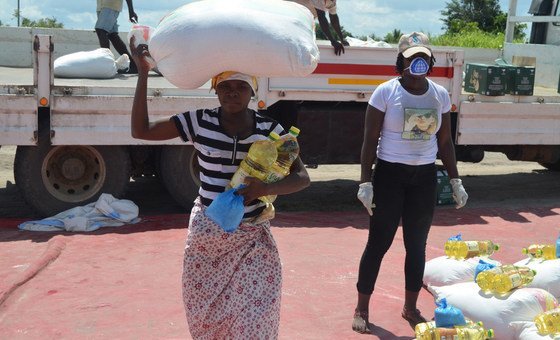 Em Moçambique, mulher coleta alimentos para duração de um mês. Suprimentos de longo prazo reduzem as chances de aglomeração.