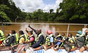 Des réfugiés ivoiriens saluent leurs amis et leur famille depuis une barge qui les ramène du Liberia en Côte d'Ivoire.