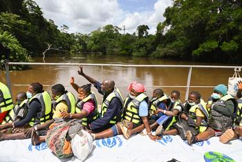 Refugiados marfileños saludan a sus amigos y familiares desde una barcaza que los transporta desde Liberia a Côte d’Ivoire.