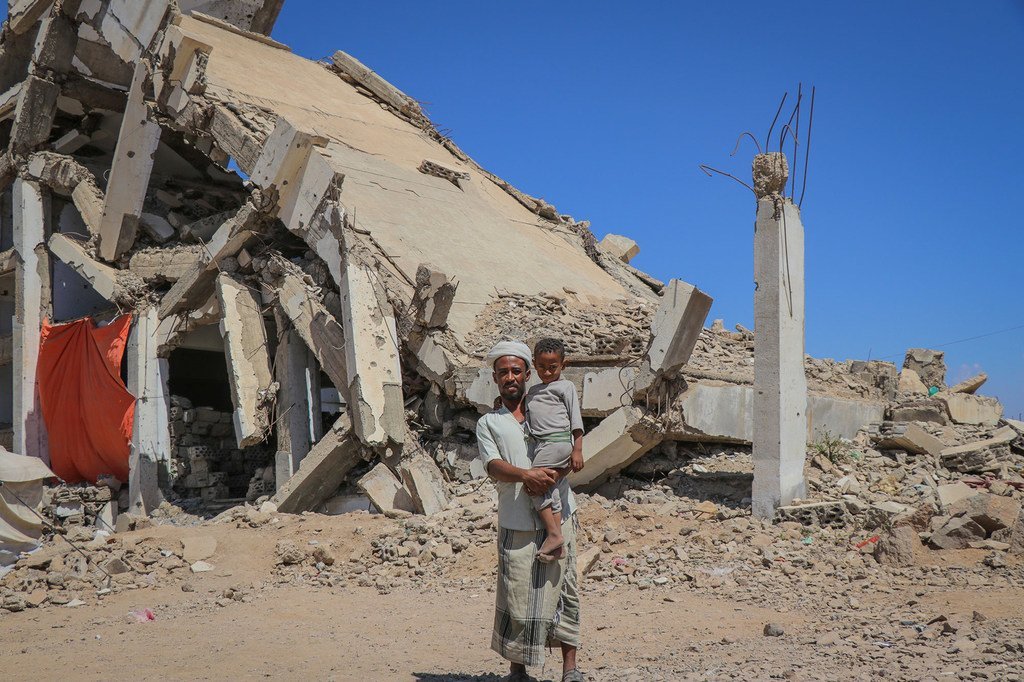 在也门的一个流离失所者营地，一名男子抱着他的孩子。