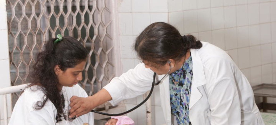 भारत में एक डॉक्टर, एक नवजात शिशु और उसकी माँ की जाँच करते हुए.
