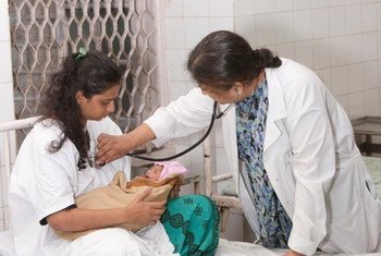 Un doctor examina a una madre con VIH y su bebé recien nacido en India.