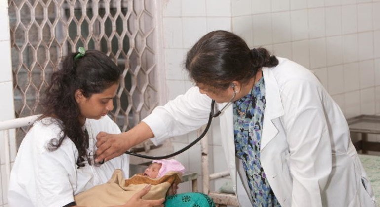 Un doctor examina a una madre con VIH y su bebé recien nacido en India.