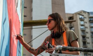 Musya Qeburia works on a piece of wall art in Tbilisi, Georgia. Her ability to leave such a visual mark on her city is a reflection of the openness Georgia has achieved with support from the UN. 