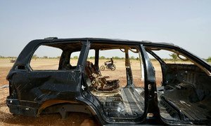 A man on a motorcycle drives by a burnt-out car in the northern region of Burkina Faso where security incidences continue to rise. (June 2019)