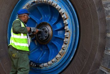 在纳米比亚的一家铀矿，一名工人正在修理一辆巨型运输卡车的车轮。