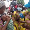 La Représentante de l'UNICEF au Bénin vaccine un enfant après que sa mère a accepté.