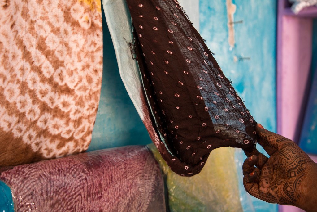 A woman's hand with henna displays a traditional Mauritanian veil in a shop.