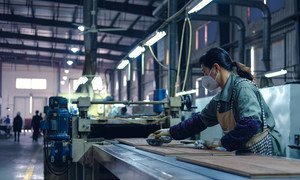 A worker cleans finished wood flooring in a factory in Zhejiang, China.