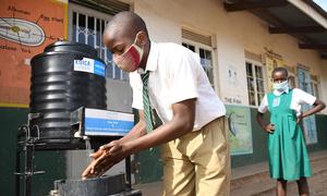 Mukasa Herbert, alumno de la Escuela primaria y guardería del asentamiento de Nakivubo en Uganda, se lava las manos el primer día de la reapertura de la escuela, el 10 de enero de 2022.