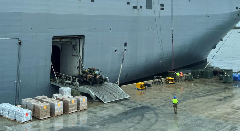 Workers load the HMAS Adelaide ship  with emergency supplies dedicated to Tonga Islands in response to the eruption of the Hunga-Tonga-Hunga-Ha'apai underwater volcano.