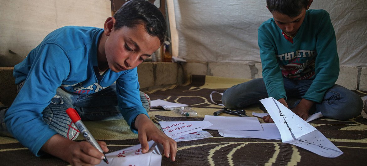 叙利亚伊德利卜的境内流离失所者营地内，两名男童正在制作纸口罩。