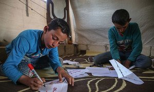 Two boys making paper masks at the Al-Tah IDP camp in Idlib Governorate, Syria.