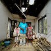 Ambuchu John is 58 years old and completely blind, seen here standing in his new home with his two eldest children, having been displaced by the fighting in Buea District, Cameroon.