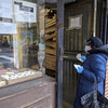 Woman waits with cash in hand to make purchase an old time New York City bakery, which counts the number of people it allows in to maintain a safe distance between customers.