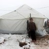 叙利亚西北部靠近土耳其边境的一处非正式定居点内，一个男孩站在一顶帐篷的入口处。