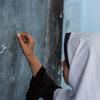 在阿富汗赫拉特市的一所学校，一名学生正在黑板上写字。 