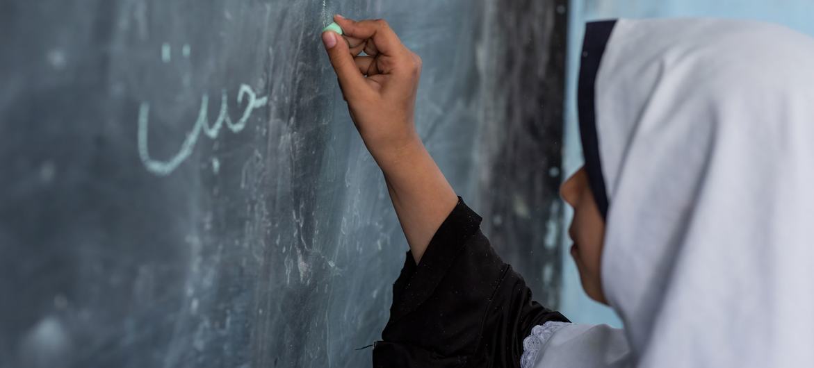 Une jeune fille afghane écrit au tableau dans une école à Hérat, en Afghanistan.