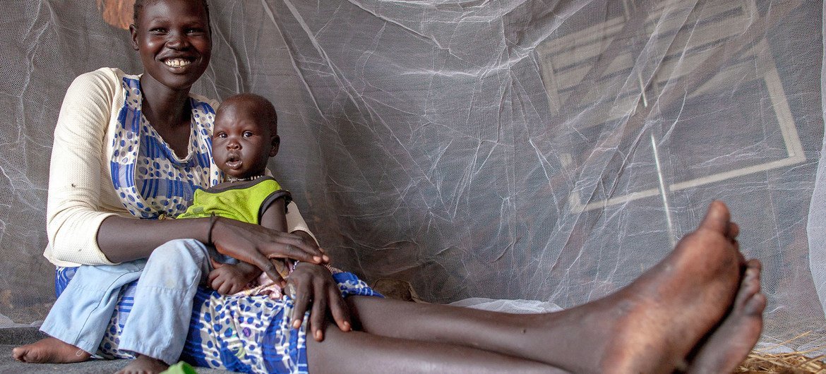 Una madre y su niño de nueve meses se sientan bajo una mosquitera antimalaria suminitrada por UNICEF en el Sudán del Sur.