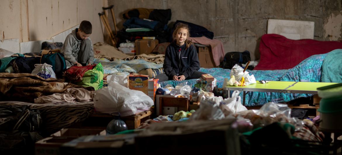 यूक्रेन के उत्तरी शहर ख़ारकीफ़ में दो बच्चे, एक अस्थाई बचाव शिविर में बैठे हुए जो सुरक्षा की ख़ातिर एक भूमिगत कार पार्क में बनाया गया है.