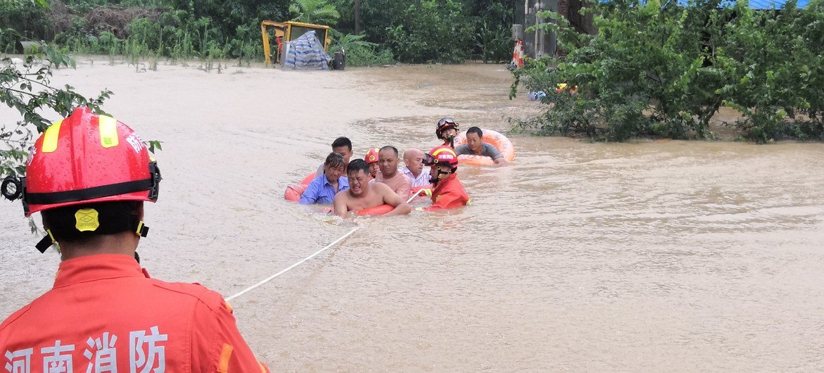 عمال الإنقاذ يقومون بإنقاذ القرويين من مياه الفيضانات في مدينة شينغيانغ بمقاطعة خنان الصينية.