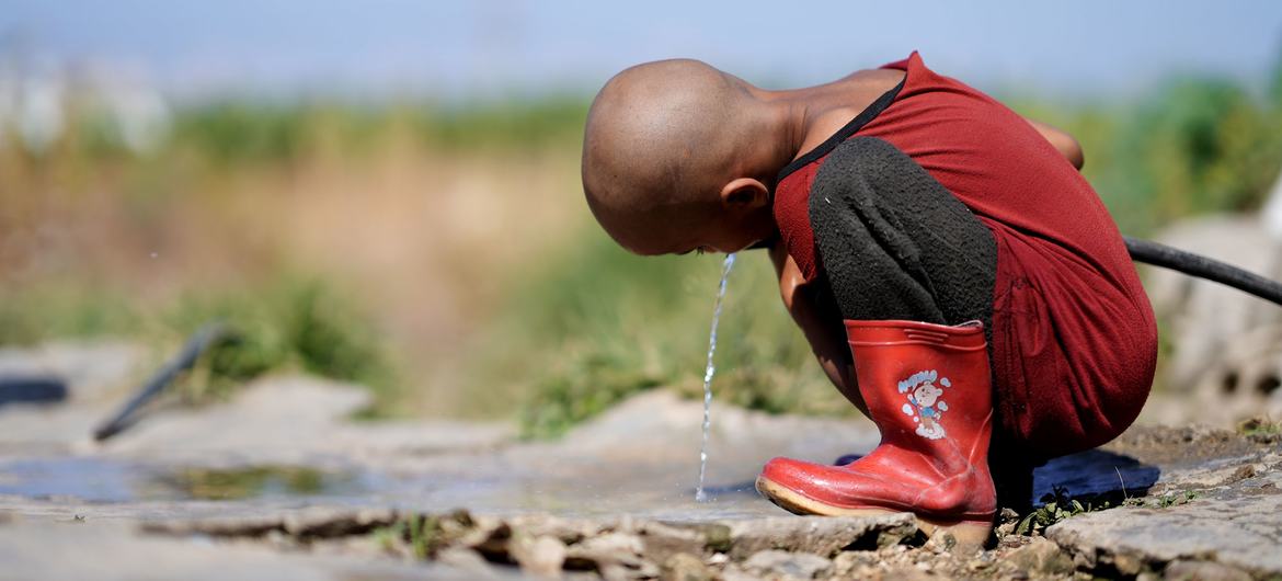 طفل يشرب الماء من المصدر الوحيد في مخيم الحسبي في صيدا، لبنان.