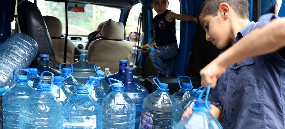 عائلة تنقل عبوات من المياه من نبع بسبب النقص الإمدادات في لبنان.