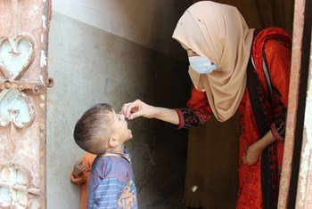 पाकिस्तान में यूनीसेफ़ की स्टाफ़ सदस्य हुसना गुल पोलियो टीकाकरण अभियान के तहत एक बच्चे को वैक्सीन पिलाते हुए.
