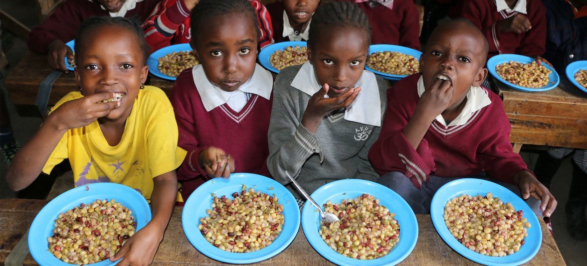 केनया के एक स्कूल में भोजन खाते बच्चे. ये भोजन ऐसी सब्ज़ियों से तैयार किया गया है जो कुछ असमान्य आकार की थीं और उन्हें निर्यात के लिये उपयुक्त नहीं समझा गया.