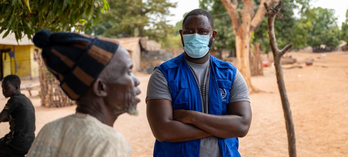 Un travailleur de l'OIM à l'écoute d'un chef de communauté dans un village gambien.