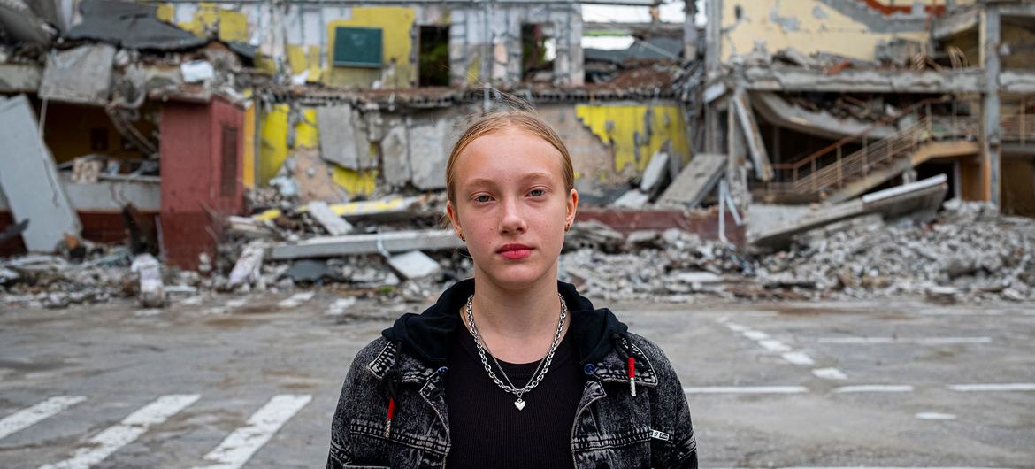 A twelve-year-old girl stands in front of her school which was destroyed in an air strike during the conflict in Kharkiv, Ukraine.