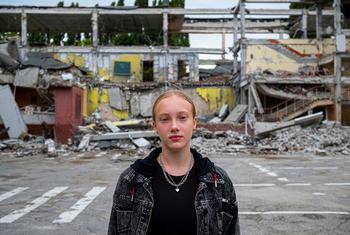 यूक्रेन के ख़ारकीव में एक 12 वर्षीय लड़की अपने स्कूल के बाहर खड़ी है, जोकि हवाई बमबारी में ध्वस्त हो गया था.