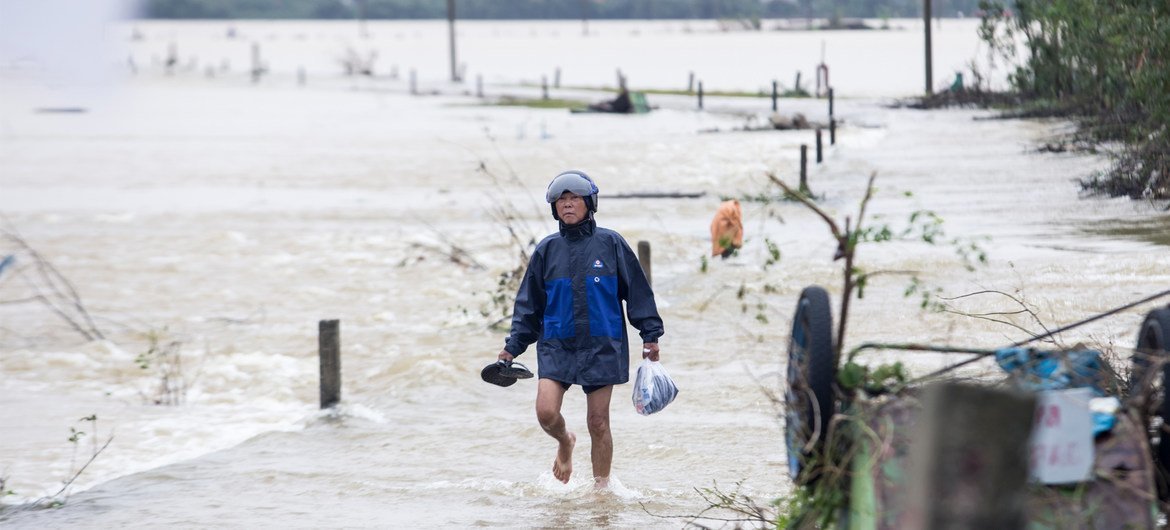 10月20日，越南承天顺化省的居民趟着洪水前往救助物资领取点。