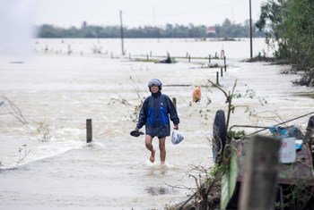 10月20日，越南承天顺化省的居民趟着洪水前往救助物资领取点。
