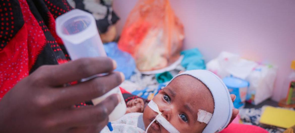 فاطمة تحمل ابنها أثناء تلقيه العلاج من سوء التغذية الحاد الوخيم في مستشفى في عدن، اليمن.