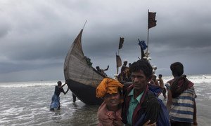 一名罗兴亚难民乘船抵达孟加拉国的考克斯巴扎尔，一名男子帮助她登陆。 （资料）