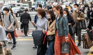 People with protective masks walk in the street of Tokyo, Japan.