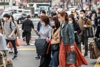 أشخاص يرتدون كمامات واقية يسيرون في أحد شوارع طوكيو باليابان.