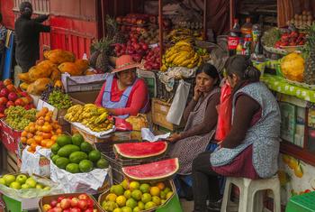 Women fruit and vegetable vendors chat at a market in La Paz, Bolivia. 