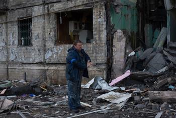 رجل يقوم بإزالة الحطام من أمام بناية في العاصمة كييف.