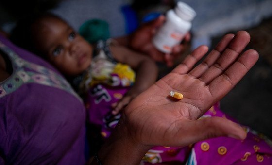 Mãe em Mbarara, no Uganda, dando medicamento contra HIV a seus filhos