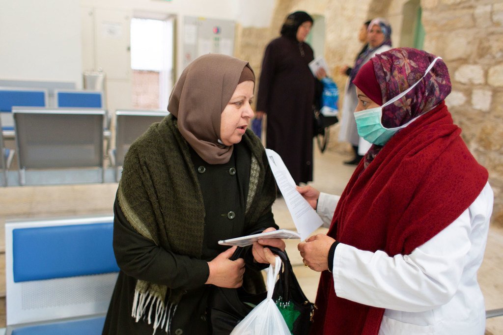 Une agente de santé fournit des informations sur la Covid-19 à une patiente du centre de santé de Jérusalem.