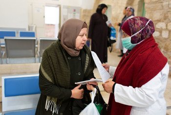 عاملة في مجال الصحة تقدم المعلومات حول كوفيد-19 لسيّدة في إحدى العيادات الطبية في القدس.