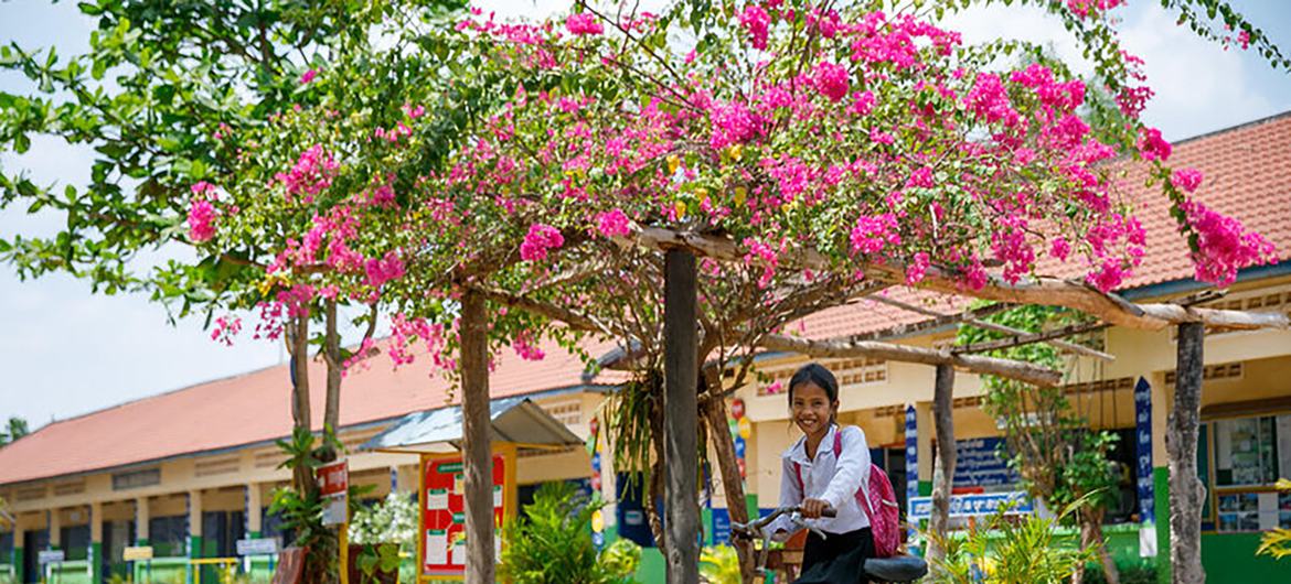 طالبة تقود دراجتها إلى المنزل من المدرسة في كمبوديا.