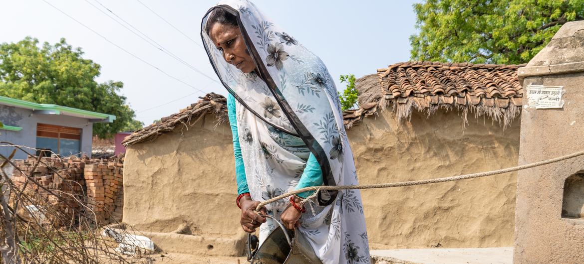 भारत के इटोरा बवानी गाँव की एक महिला दिखा रही हैं कि जल तक बेहतर पहुँच होने से पहले कैसे पानी इकट्ठा किया जाता था.