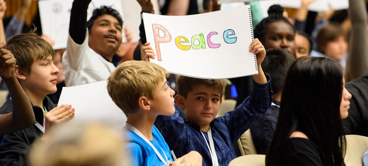 Durante un evento especial realizado para conmemorar el Día Universal del Niño, jóvenes de todo el mundo sostienen carteles que piden la paz.