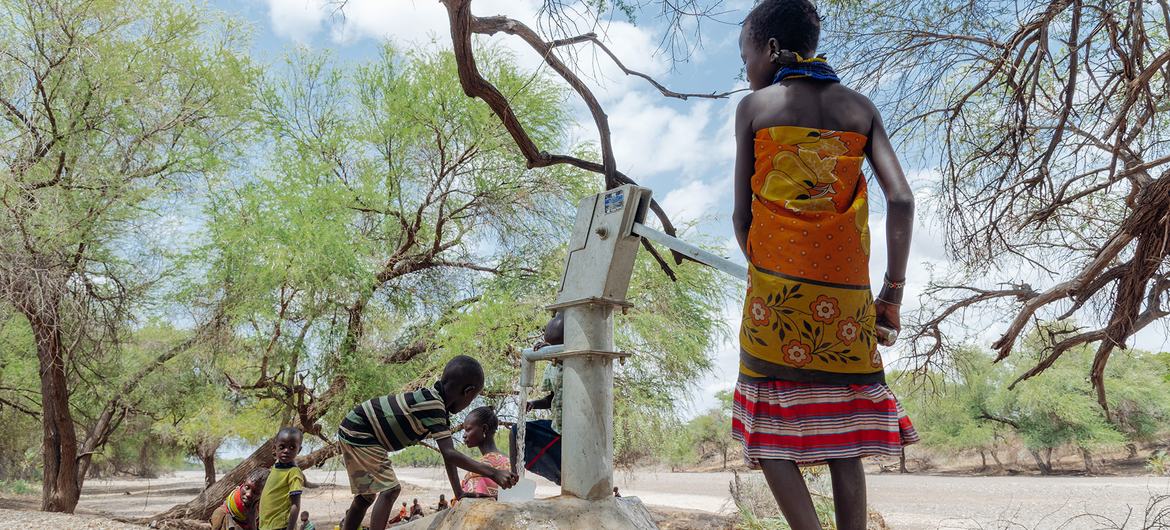 A young girl operates a hand pump near a sand dam in Turkana County, Kenya.