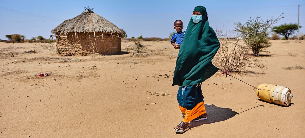 A woman walks to a water kiosk with her two-year-old son in Garissa County, Kenya.