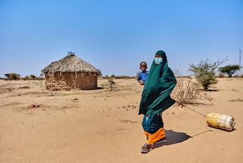 Uma mulher caminha em busca de água com seu filho de dois anos no condado de Garissa, no Quênia